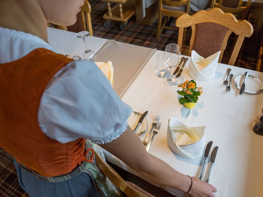 Lady arranging a dining table at Hotel & Apartments Kirchbuehl
