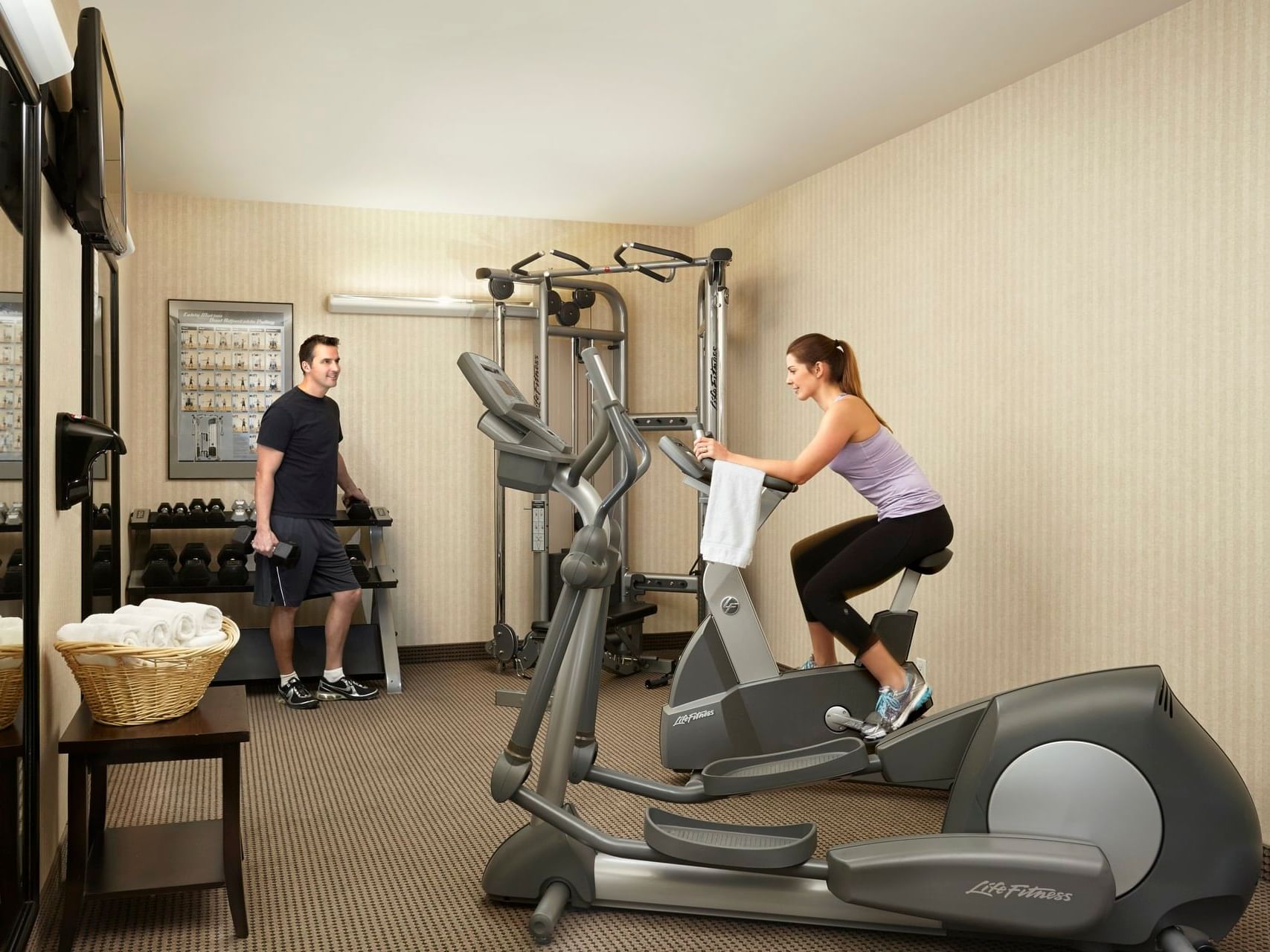 A couple using fitness room equipment at Clique Hotels