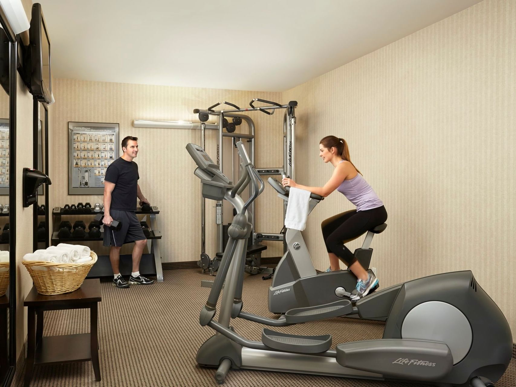 A couple using fitness room equipment at Clique Hotels