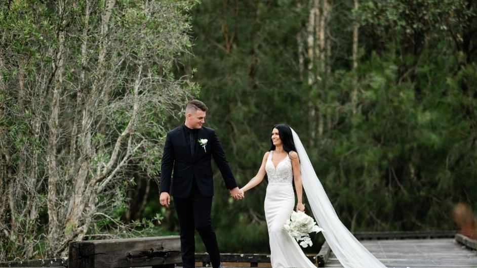 A bride and groom walking hand in hand near Mercure Kooindah Waters