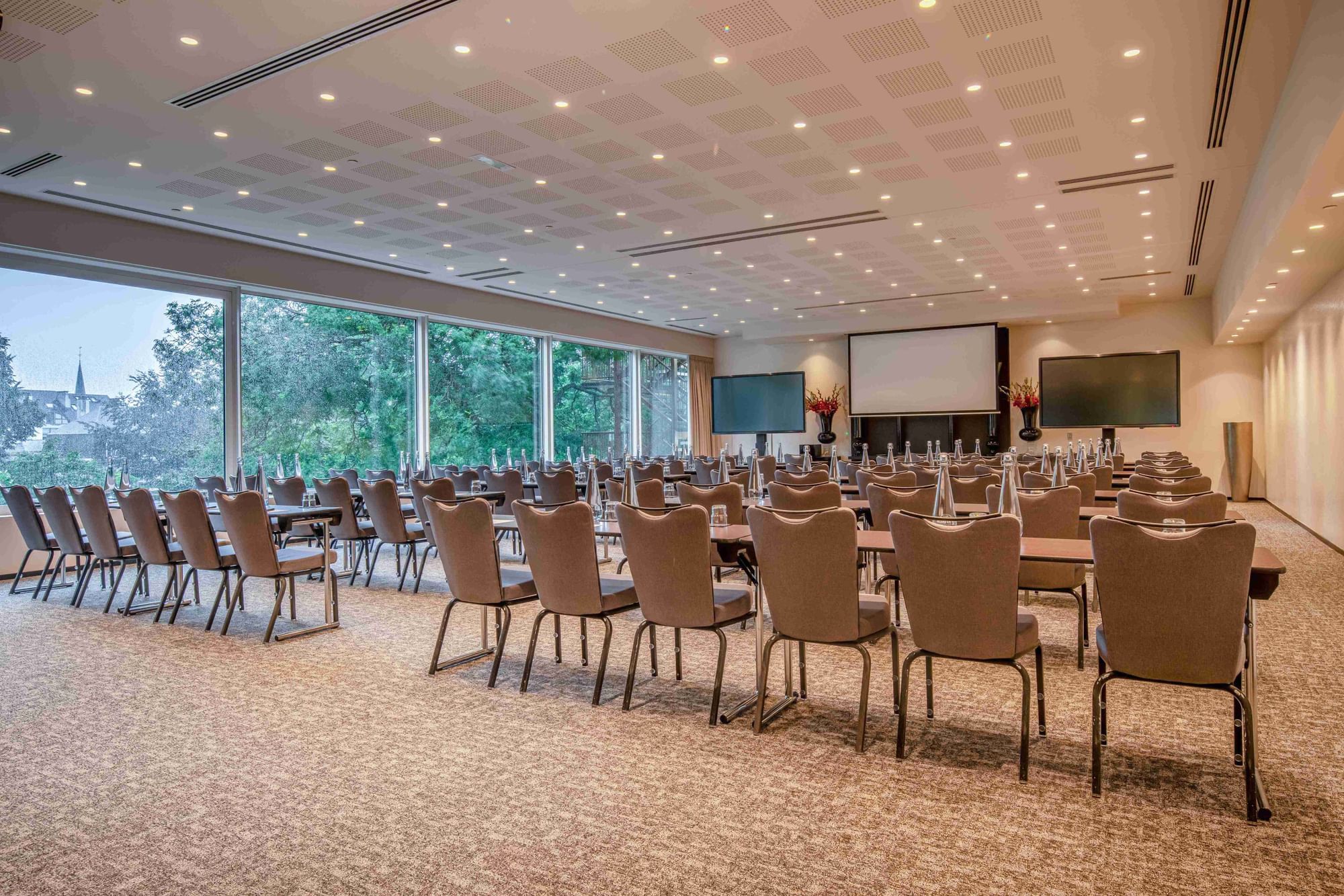 Classroom setup conference room with chairs, projector & ceiling to floor windows at The Hotels Brussels