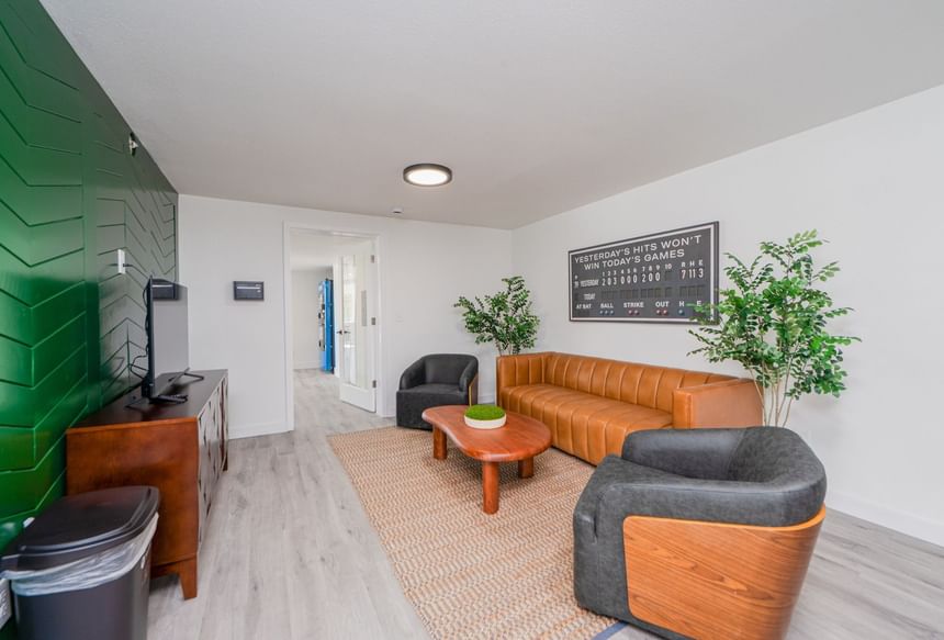Tan sofa and grey armchairs facing scoreboard wall art in the best places to stay in Washington State at The Varsity South