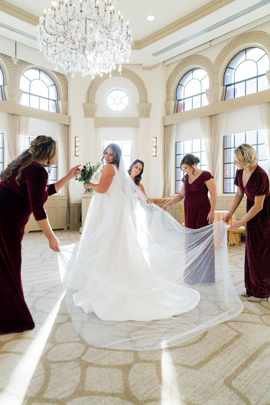 Bride with bridesmaids in maroon dresses, placed by the windows in a suite at Warwick Allerton Chicago