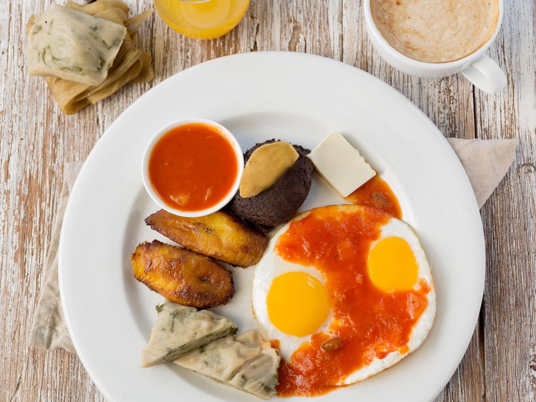 Breakfast meal with sweet fried plantains, sauce, eggs, and cheese served at Porta Hotel del Lago