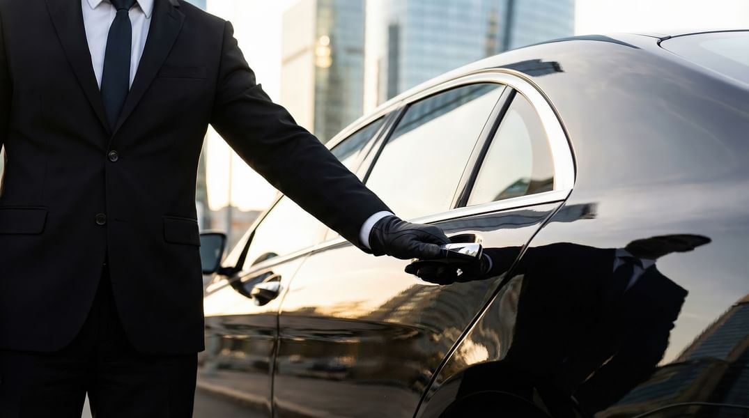 Chauffeur en costume et gants ouvrant la portière d'une voiture de luxe à Hotel Westminster Warwick Paris