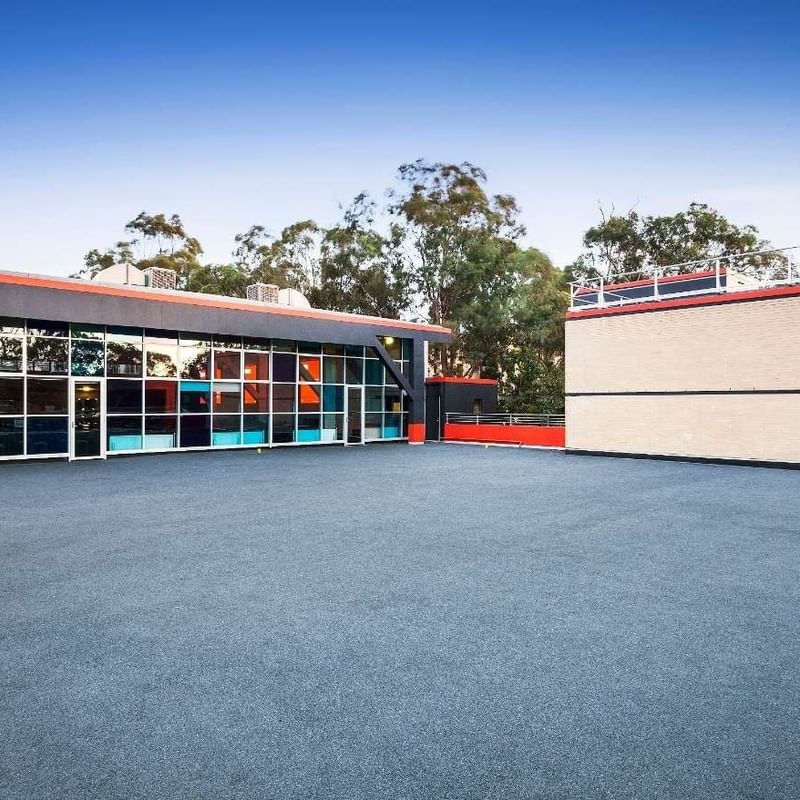 Modern building with blue and orange accents and glass facade at La Trobe University – Menzies College.