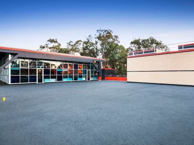 Modern building with blue and orange accents and glass facade at La Trobe University – Menzies College.