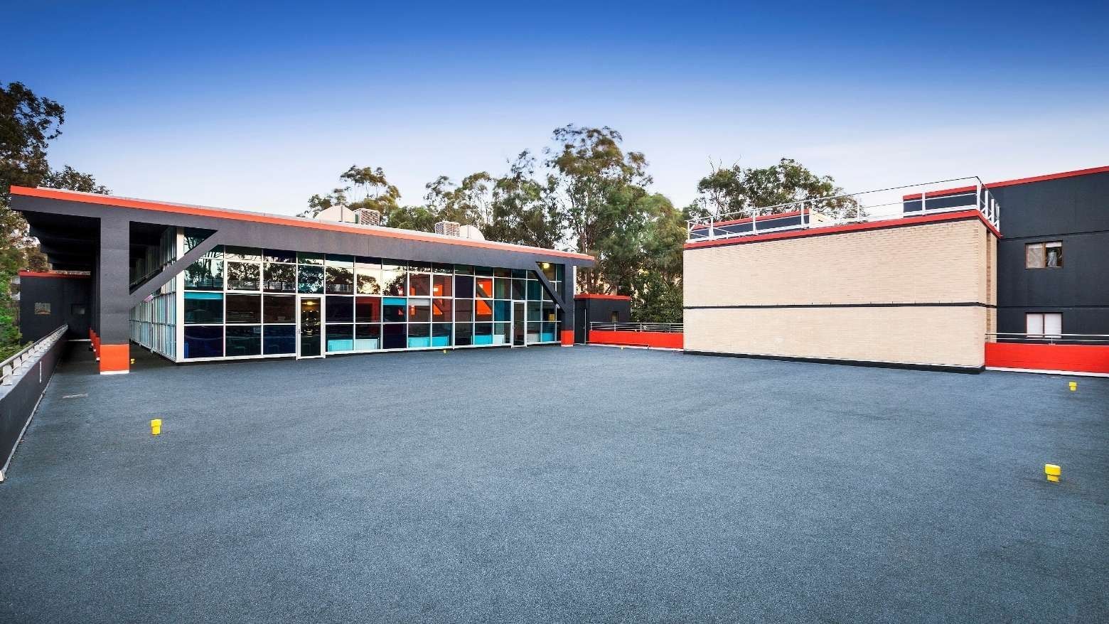 Modern building with blue and orange accents and glass facade at La Trobe University – Menzies College.