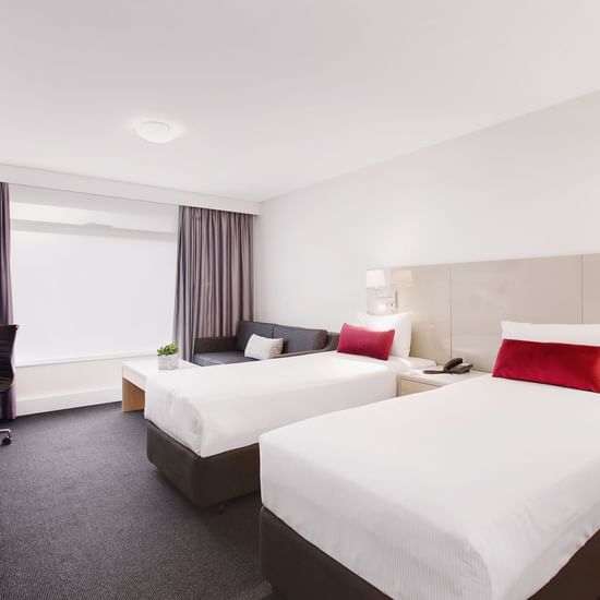 2 Queen beds and working area in Mercure Standard Room with carpeted floors at Pullman Albert Park