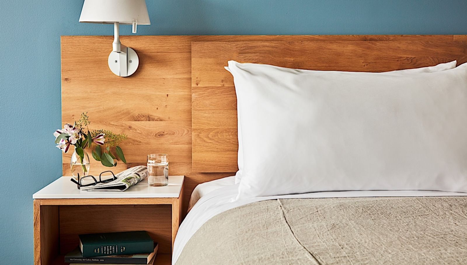 Close-up of a bed with a wall lamp in room at The Study at Yale