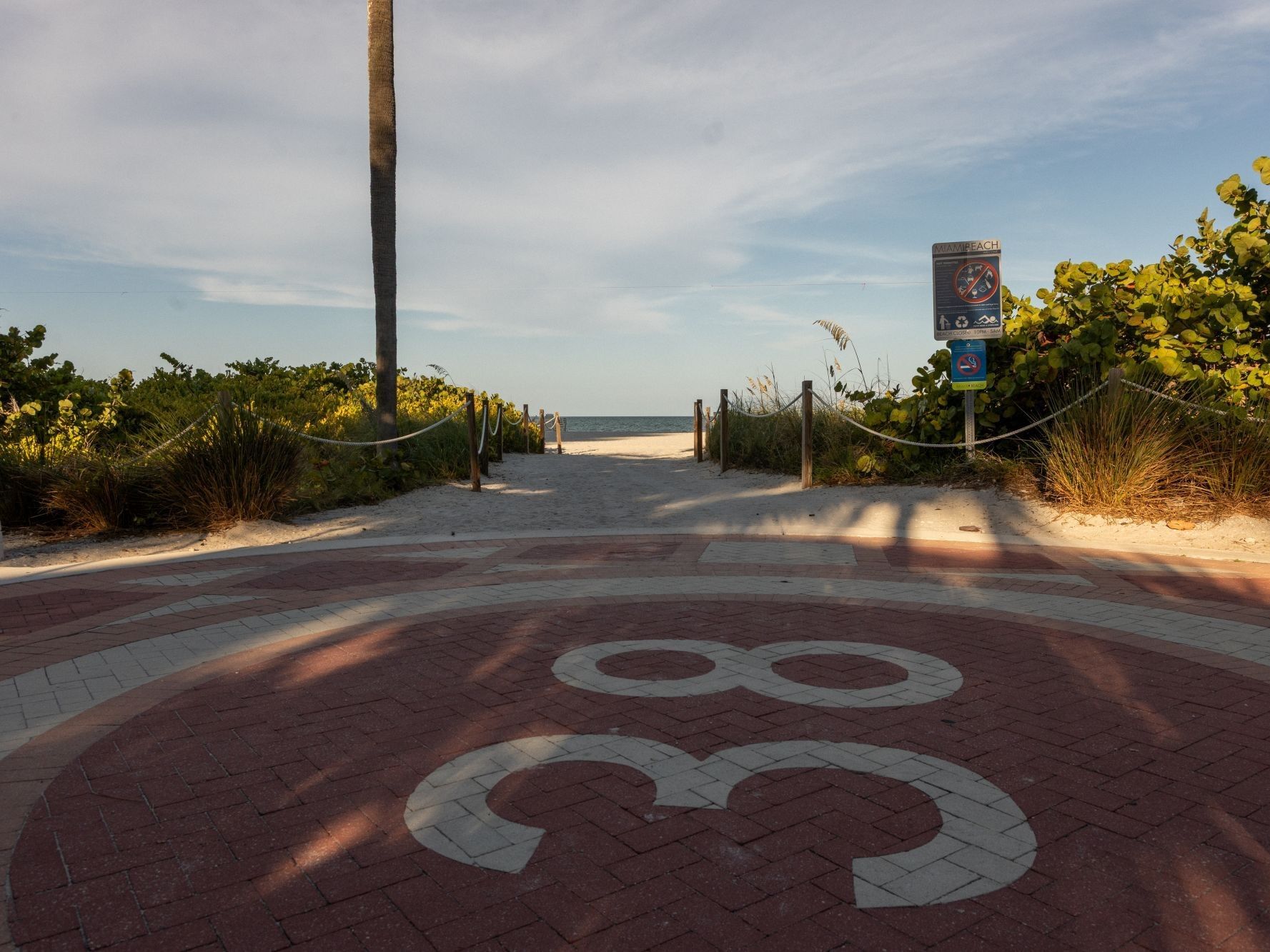 A pathway with a number 88 on it leads to the beach, with greenery and a sign on the right.