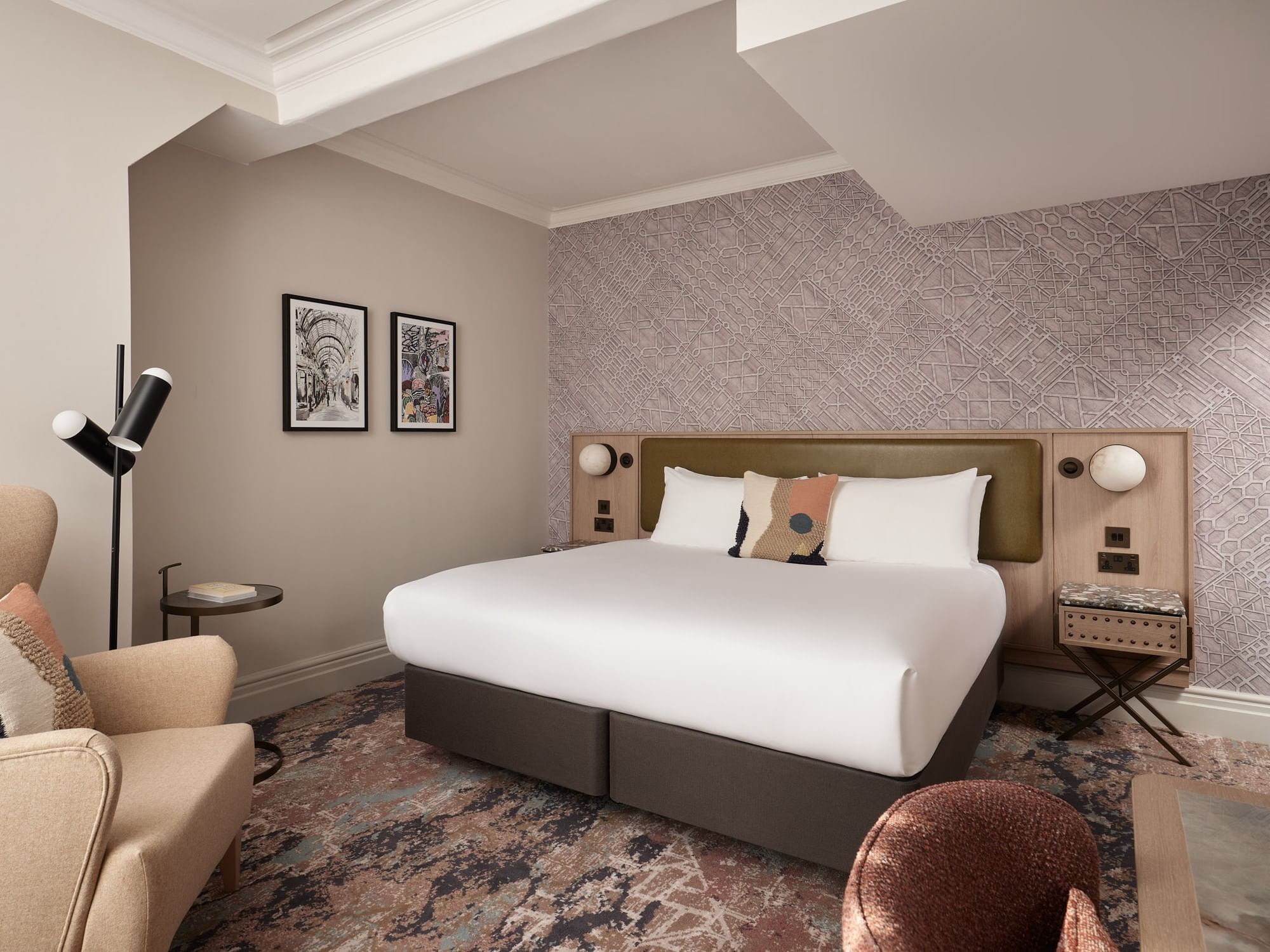 Comfortable king-sized bed and armchair in  Deluxe Double Room with patterned wallpaper at The Met Hotel Leeds, England