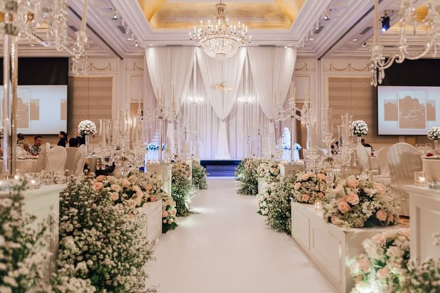 An elegant wedding venue featuring a floral aisle, chandeliers, and draped curtains at Park Hyatt Saigon