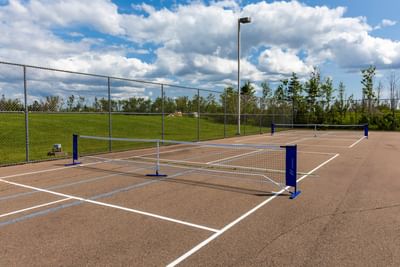 Pickleball courts with nets next to a chain-link fence under a cloudy sky at Rodd Crowbush Golf & Beach Resort