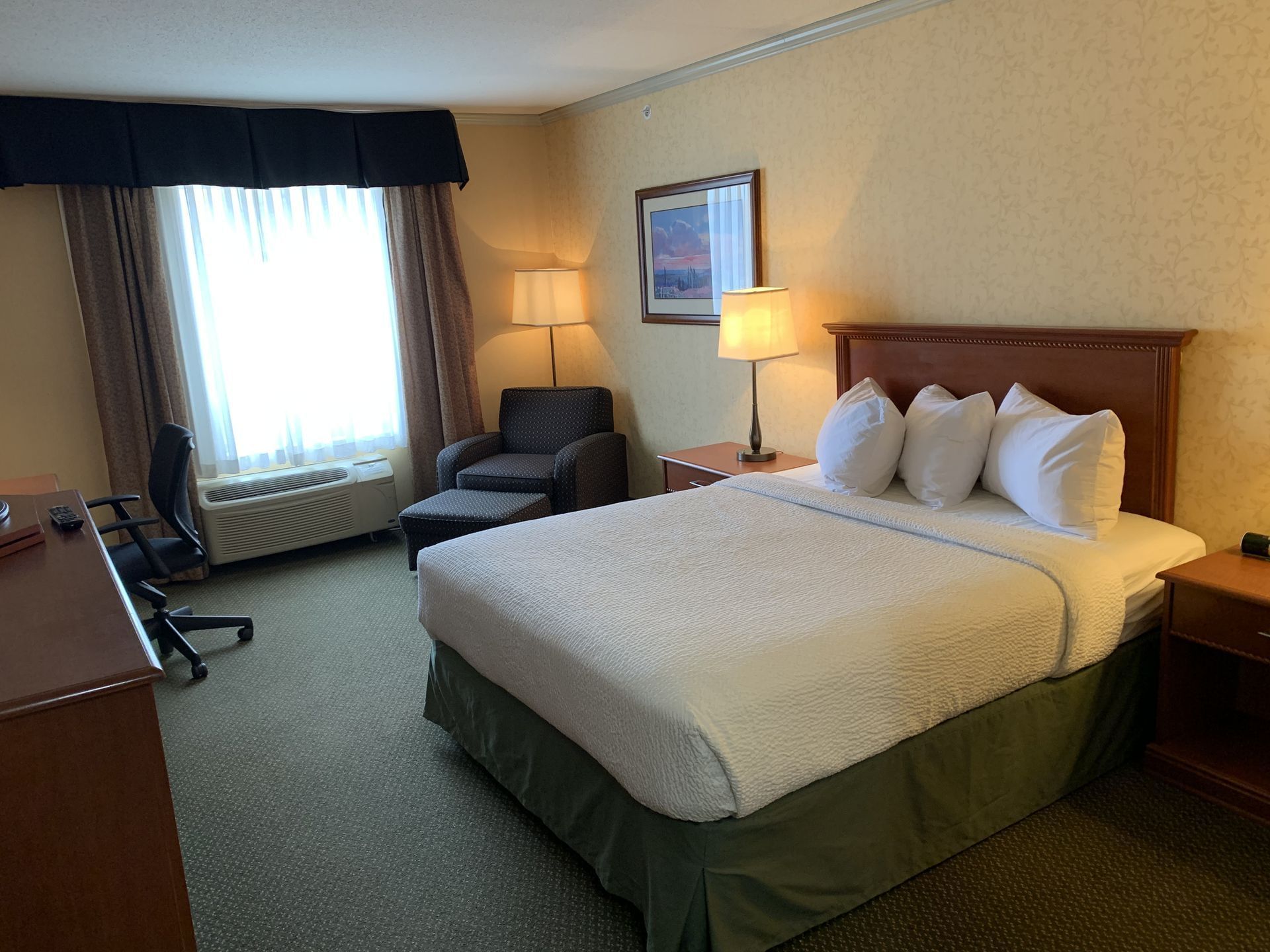 Workspace and lounger by the bed in Standard Room - One Queen at Merit Hotel & Suites