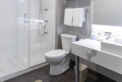 White towels on a wall rack by a toilet under a mirror at Rodd Miramichi River, best places to stay in Miramichi