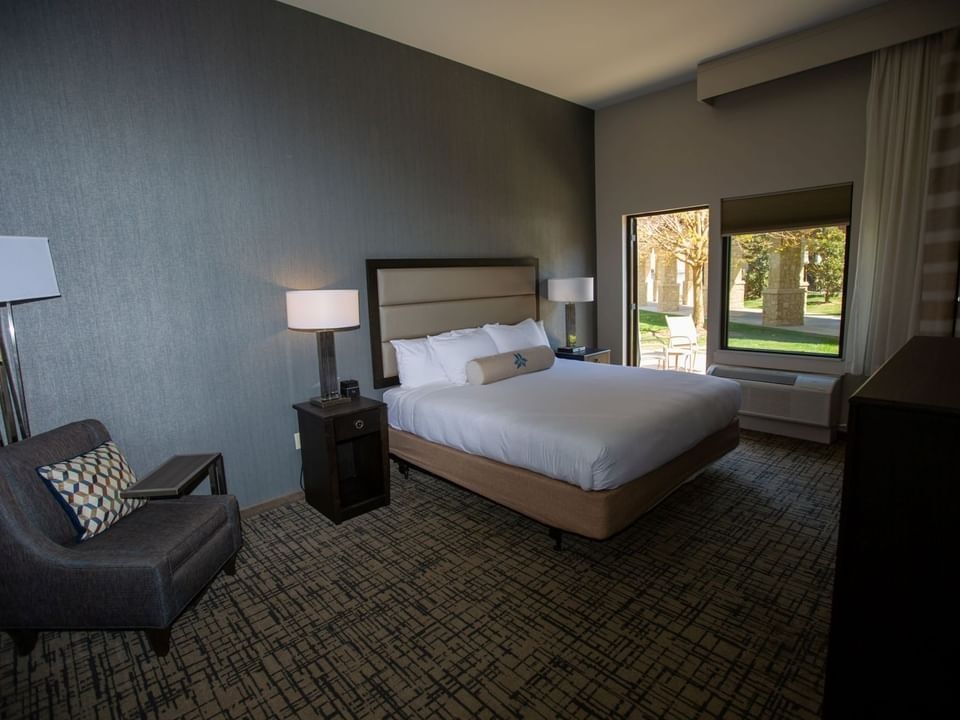 Coxy lounge chair and side cupboard by the bed in King Patio Room at Shangri-La Resort and Golf Club