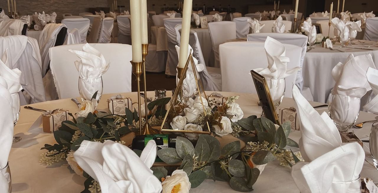 Table with candles, flowers, napkins, and glasses.