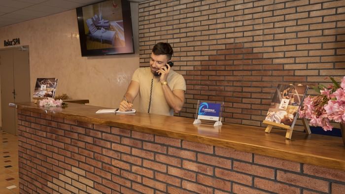 A receptionist at the reception desk in Relax'Otel