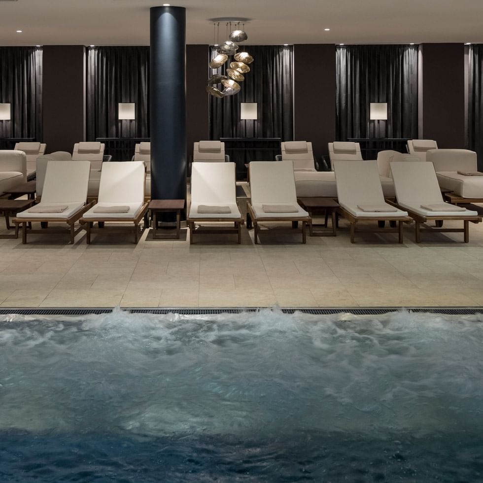 Lounges in the indoor pool area in spa at Falkensteiner Hotels