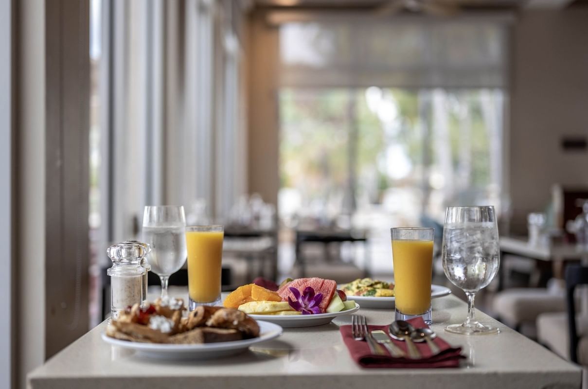Juice and fruit by breakfast plates surrounding an orchid flower in Verandah at Warwick Paradise Island Bahamas