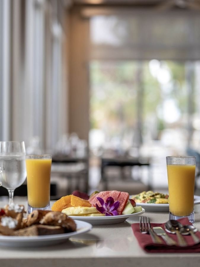 Juice and fruit by breakfast plates surrounding an orchid flower in Verandah at Warwick Paradise Island Bahamas