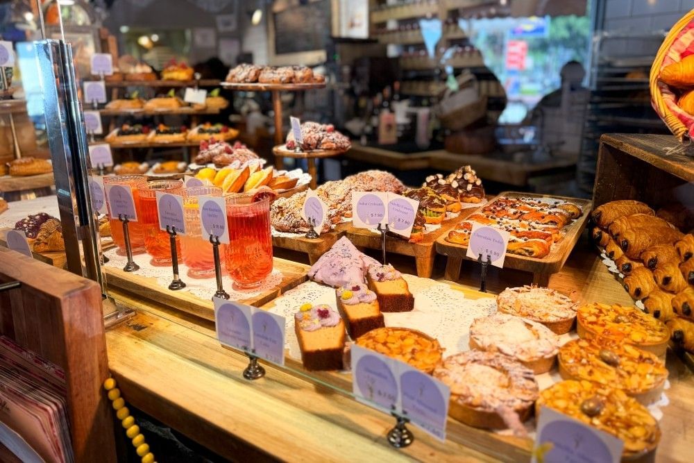 A display of pastries and beverages adorned with small purple identification signs at a bakery in Winter Garden.