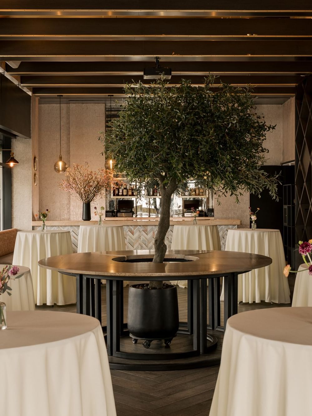 The Loft features elegant cocktail tables with floral centerpieces and decorative trees at Gansevoort Meatpacking NYC - NEW.
