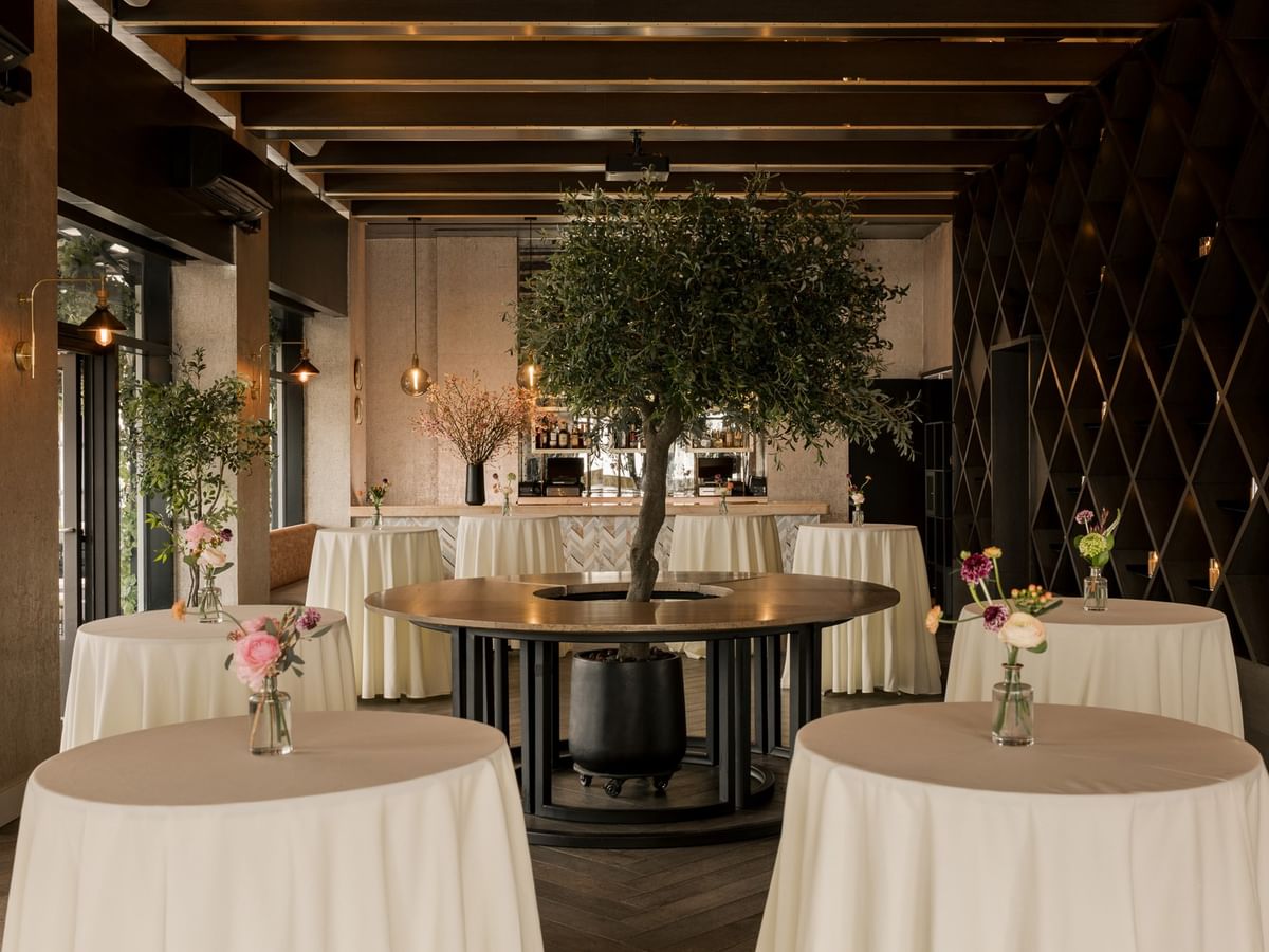 The Loft features elegant round tables with white linens and decorative trees at Gansevoort Meatpacking NYC - NEW.