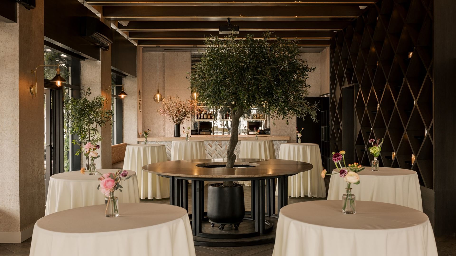 The Loft features elegant round tables with white linens and decorative trees at Gansevoort Meatpacking NYC - NEW.