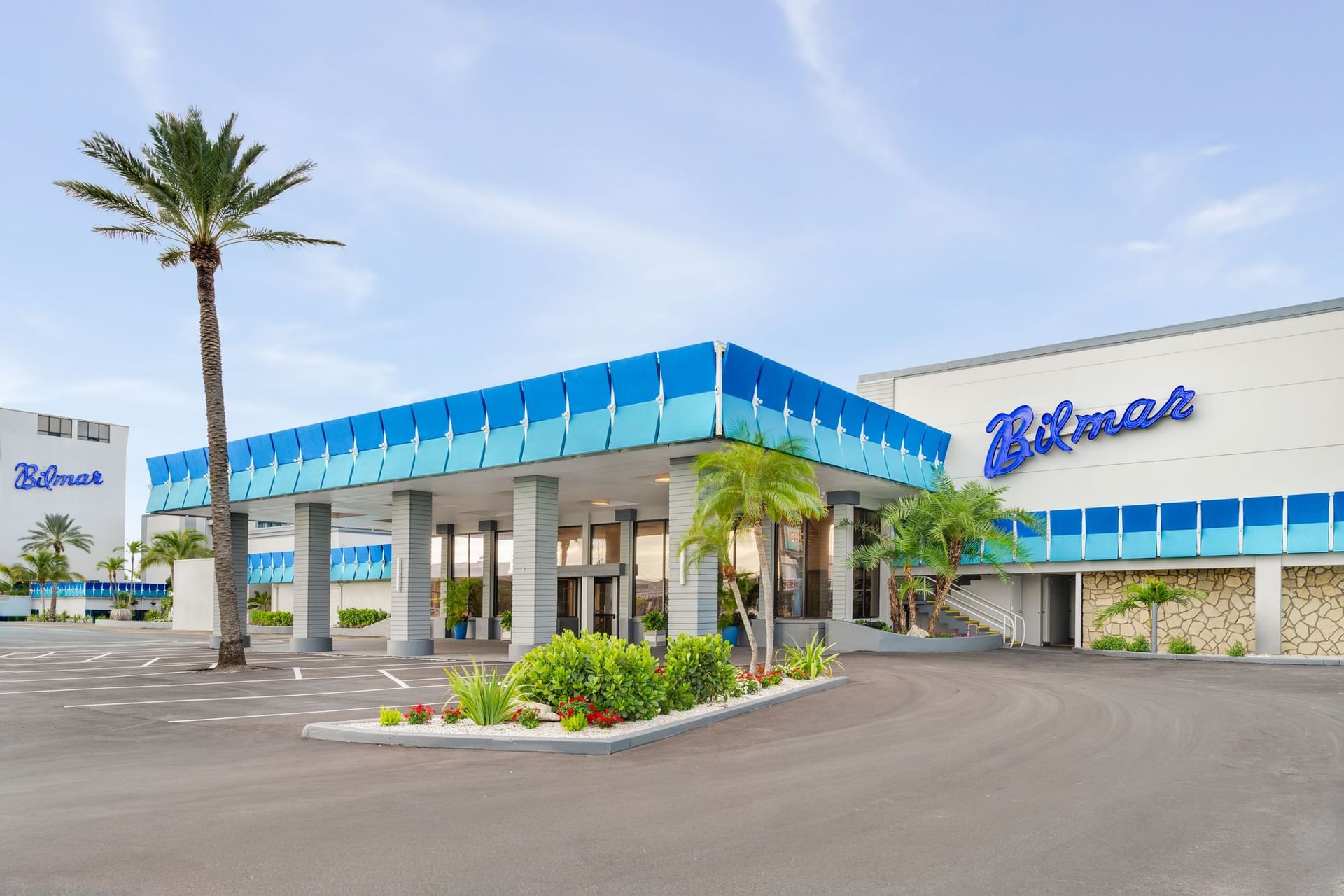 The exterior of a building with a blue and white facade and a large parking lot.