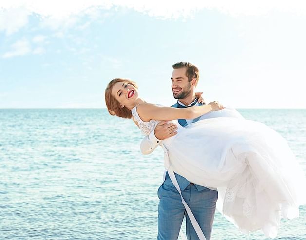 A groom holding bride for an outdoor photoshoot at Copamarina