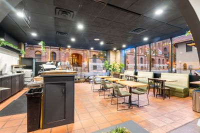 Interior of Coffee Bar at The Riverwalk Plaza Hotel with wooden tables, seating, and large windows showing an urban view