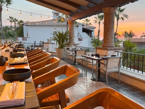 Terraza La Terraza del Santo con una larga mesa de madera al atardecer con palmeras en Hacienda del Mar Los Cabos