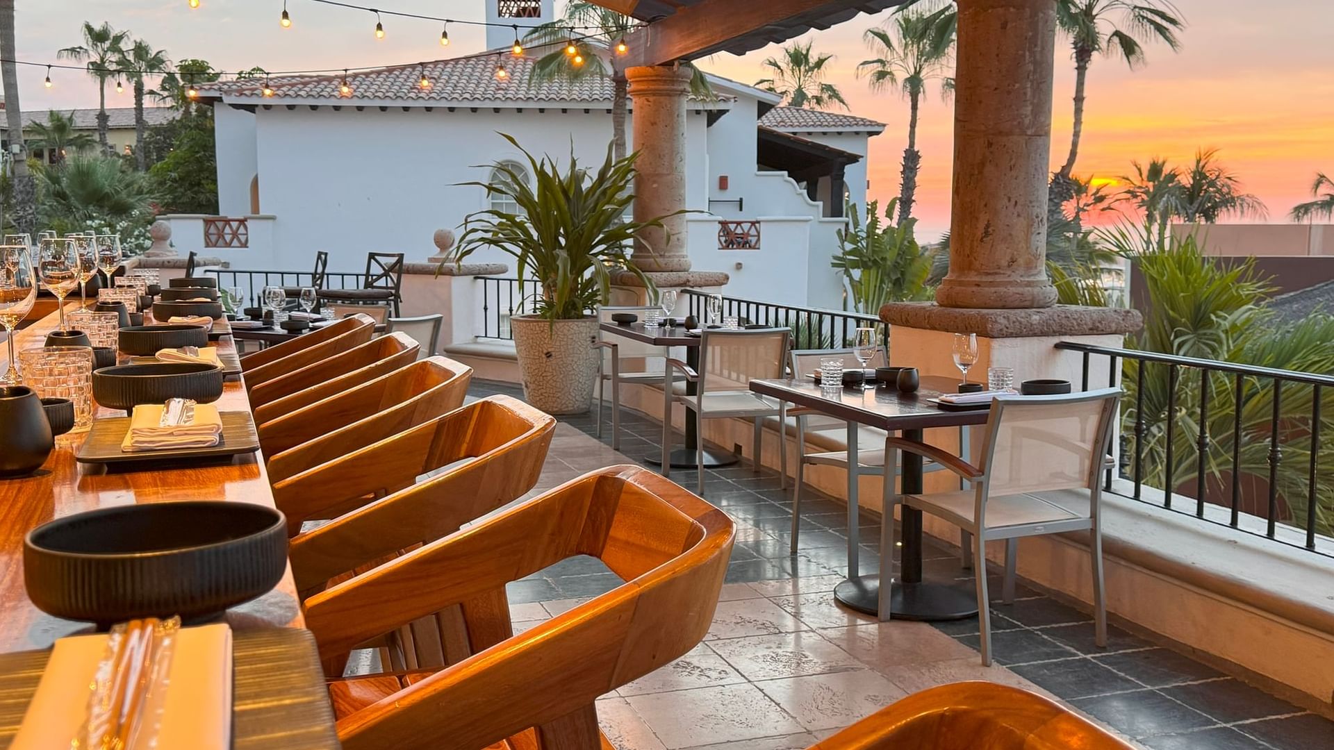 Terraza La Terraza del Santo con una larga mesa de madera al atardecer con palmeras en Hacienda del Mar Los Cabos