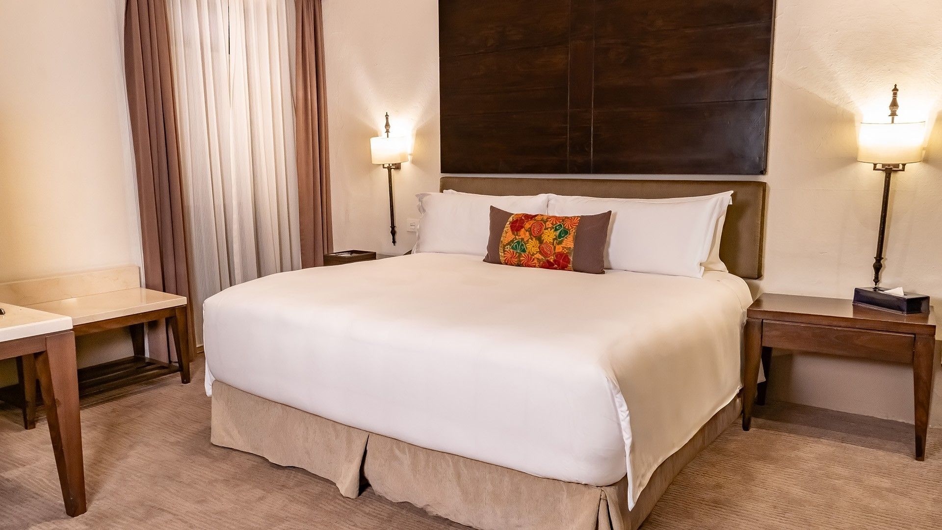 King bed with white linens and a colorful accent pillow in the King Presidential Suite at Quinta Real Puebla