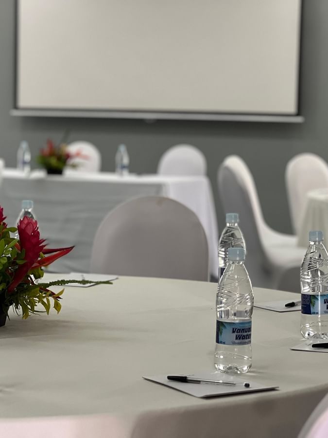 Water bottles and pens on white tables by chairs in Marquee Meeting Room Warwick Le Lagon Port villa