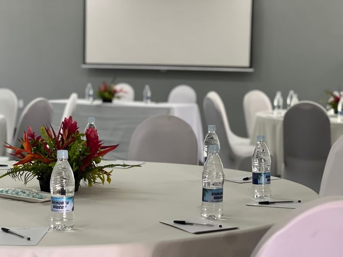 Water bottles and pens on white tables by chairs in Marquee Meeting Room Warwick Le Lagon Port villa