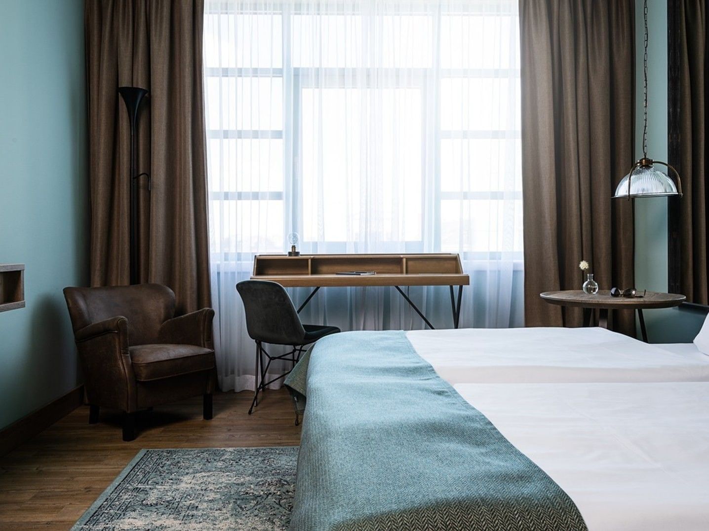 Cozy hotel room with desk, bed, and chair at Abion Spreebogen Waterside Hotel Berlin.