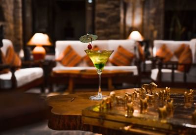 A vibrant green cocktail garnished with a cherry and served on a wooden table in Fusion Bar at Dwarika's Hotel Kathmandu