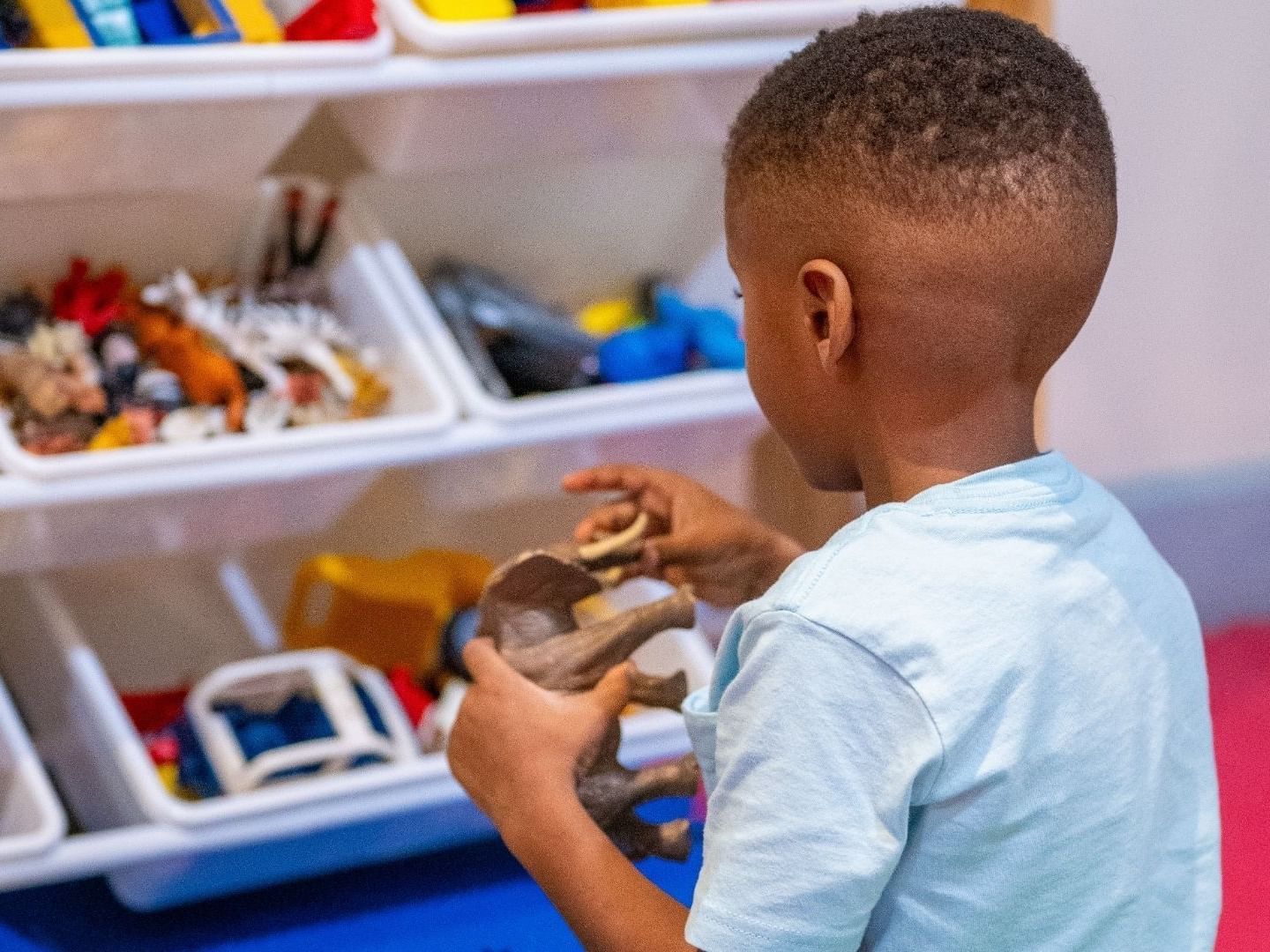 Young boy holding a toy in a room filled with toys at Savannah Beach Hotel.