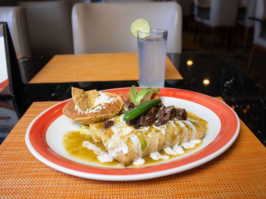 Enchiladas cubiertas con salsa verde y crema, servidas con frijoles refritos en Cafetería Palmira de Araiza Calafia