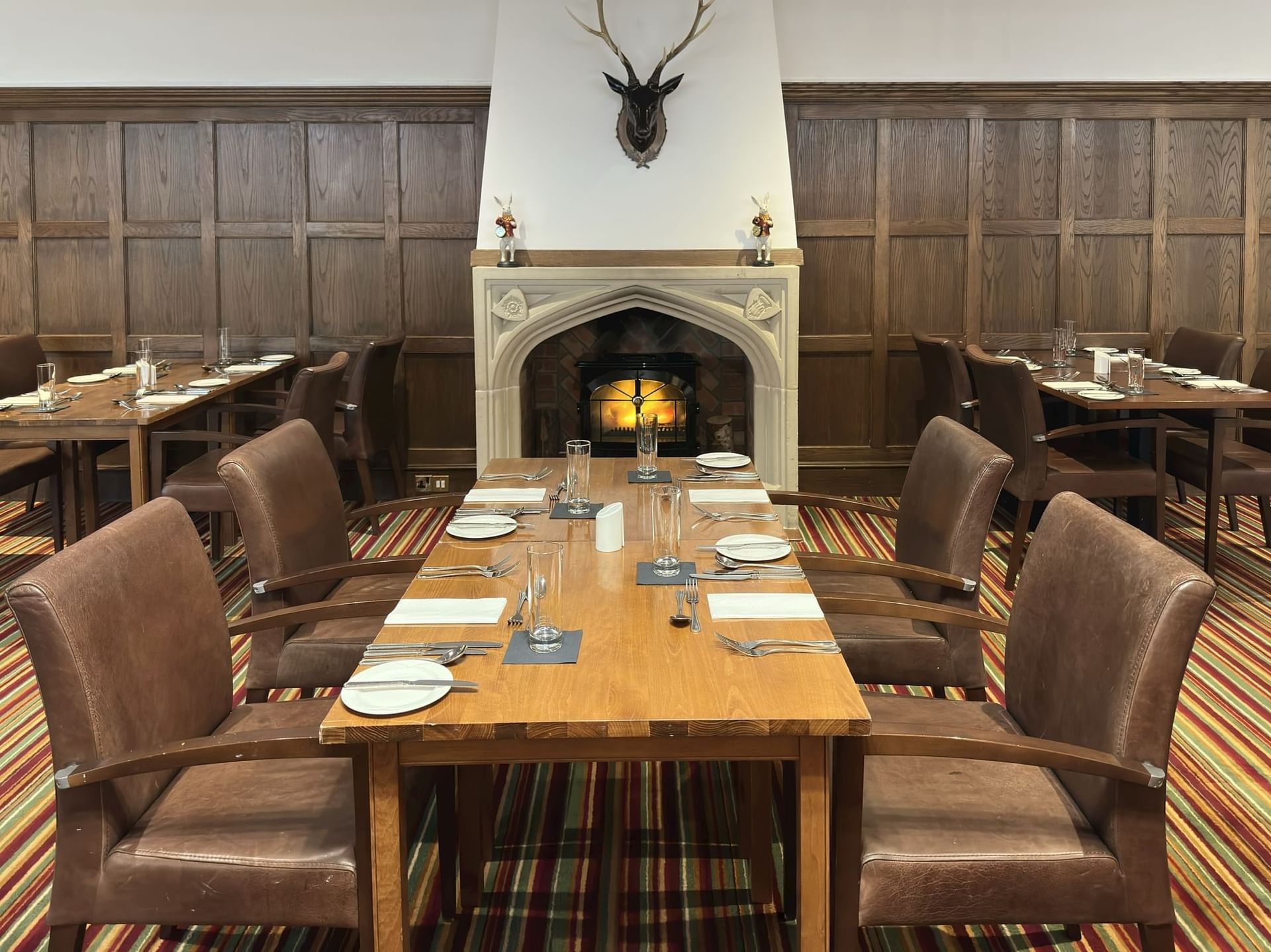 Cozy dining room with wooden paneling, an inviting fireplace, and stylish tables set for a meal at The Aberdeen Dyce Hotel