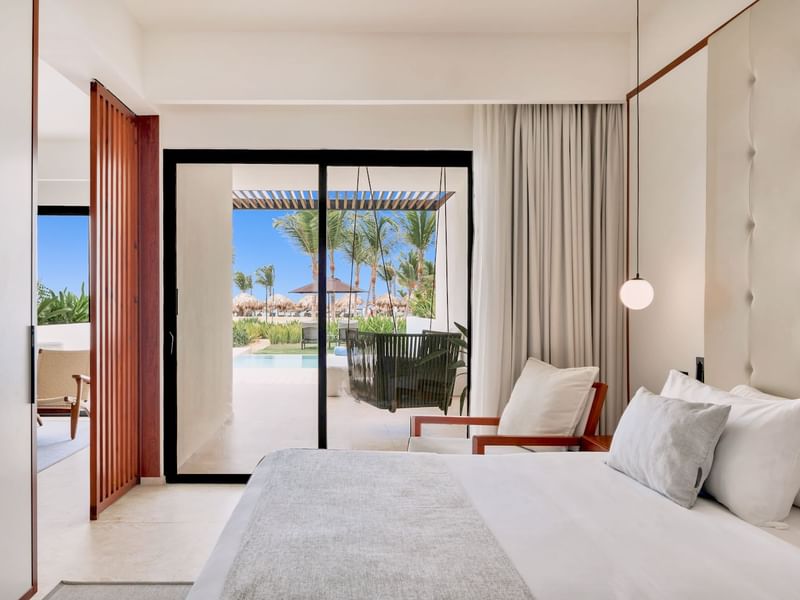 Bed and cozy chair with pool view in Tierra Suite at Live Aqua Punta Cana