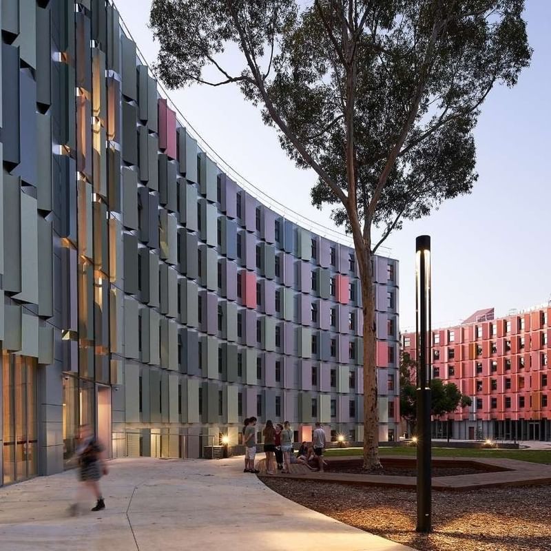 Modern student housing with vibrant facades and people walking at La Trobe University.