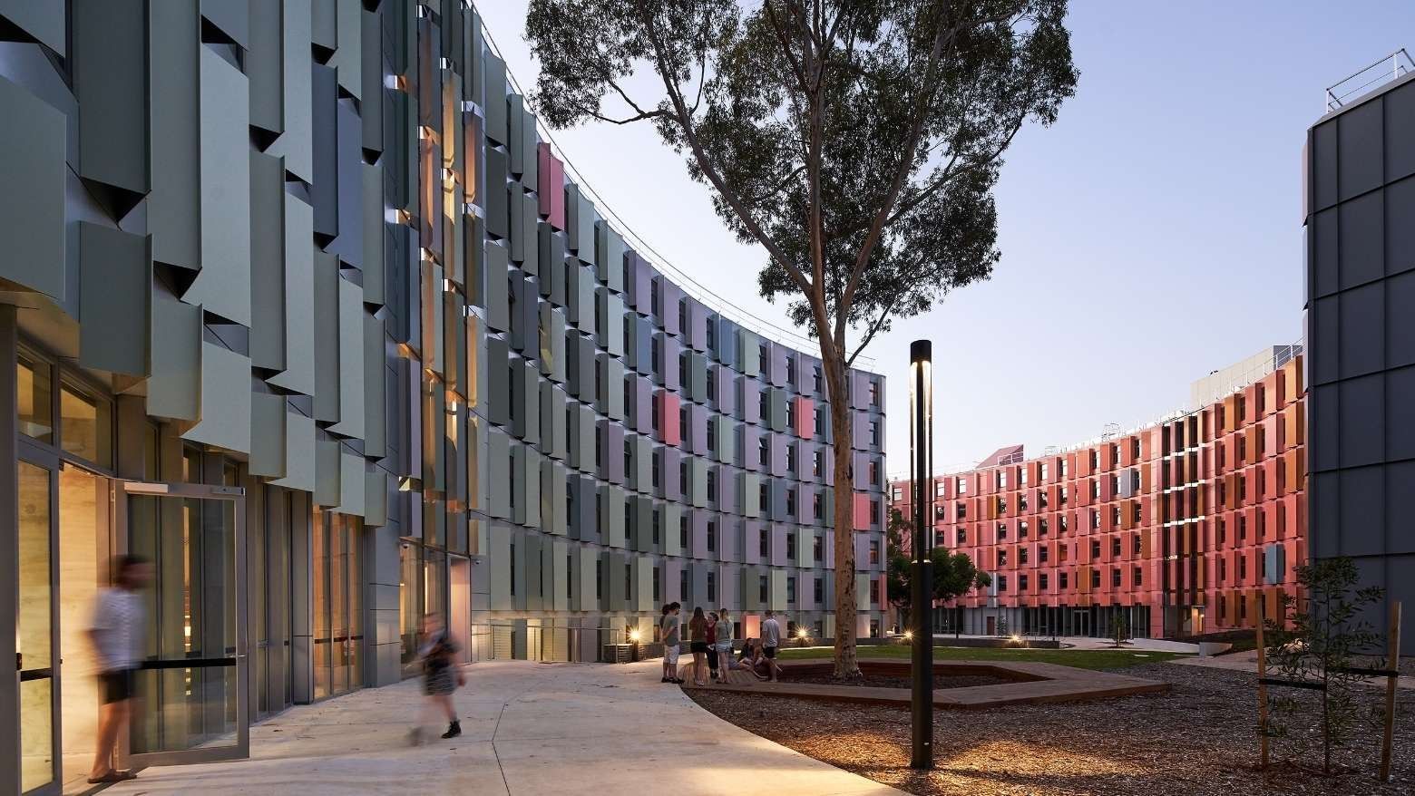 Modern student housing with vibrant facades and people walking at La Trobe University.