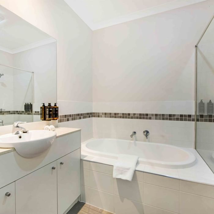 Bathroom with white vanity, basin, bathtub, and glass shower partition in Two Bedroom Apartment at Mercure Kooindah Waters
