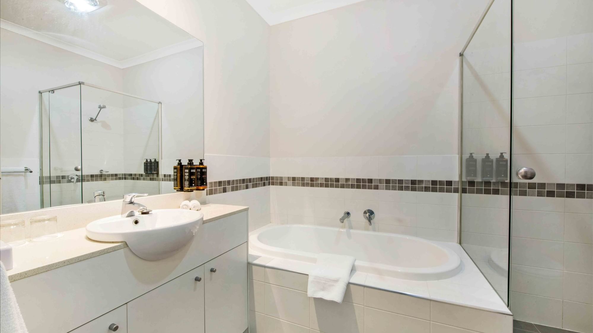 Bathroom with white vanity, basin, bathtub, and glass shower partition in Two Bedroom Apartment at Mercure Kooindah Waters