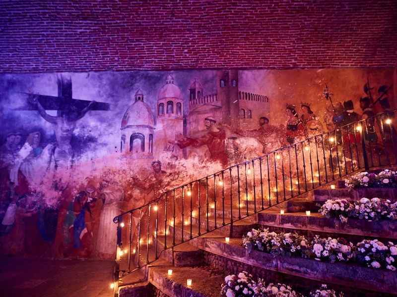 Stairway adorned with candles and a mural on the wall at Fiesta Americana