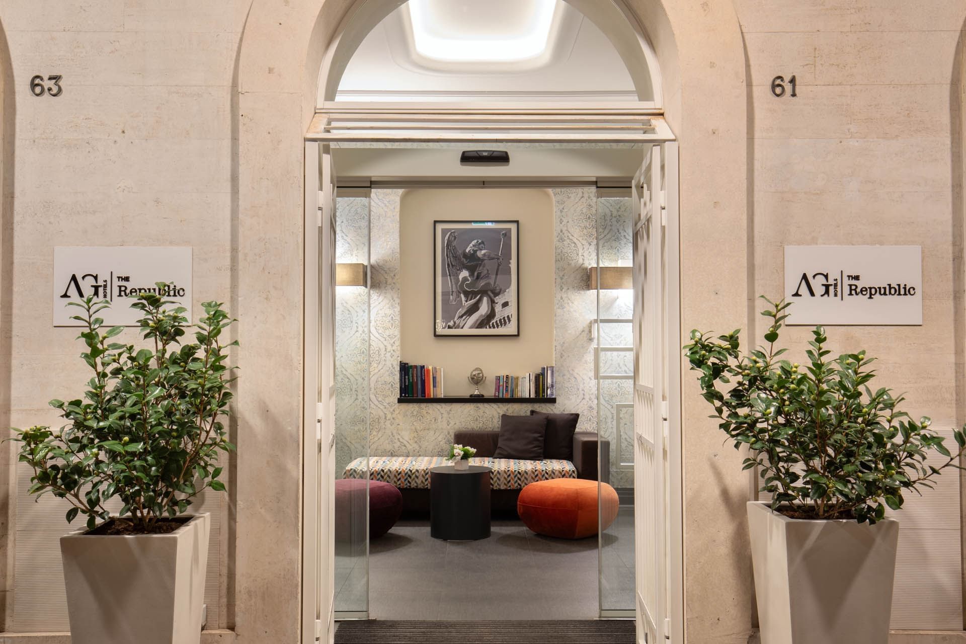 View into a stylish lobby with comfy seating, greenery, framed by an elegant entrance and signs for The Republic Hotel
